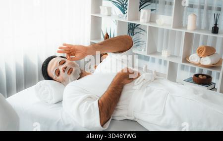 Ambiance de lumière du jour moderne et sereine du salon de spa, la cliente s'adonne à rajeunir avec le masque de soin du visage. Soin et beauté de la peau du visage Banque D'Images