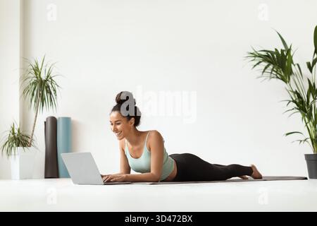 Cours de yoga en ligne avec entraîneur féminin à l'aide d'un ordinateur portable dans un studio de fitness Banque D'Images