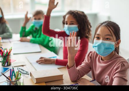 Divers enfants de l'école engagés dans des activités en classe tout en portant des masques faciaux pendant la classe Banque D'Images
