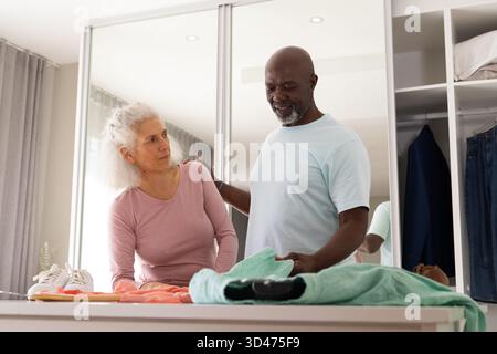 Sélection de divers couples seniors organisant des vêtements dans le vestiaire, avec chemise verte à la main Banque D'Images