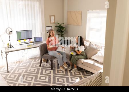 Diverses amies féminines collaborant sur la conception dans le bureau à domicile moderne, avec des nuances de couleur Banque D'Images