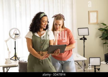 Collaboration de diverses amies féminines examinant l'écran de la tablette dans le home studio, avec lumière annulaire Banque D'Images