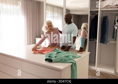 Organisation de divers couples arrangeant des vêtements dans le vestiaire avec des chaussures marron et un sweat-shirt rose Banque D'Images
