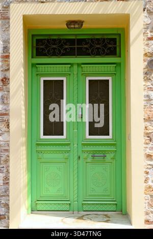 Une double porte en bois vintage vert vif dans une maison en pierre sur l'île de Lesbos, Grèce Banque D'Images