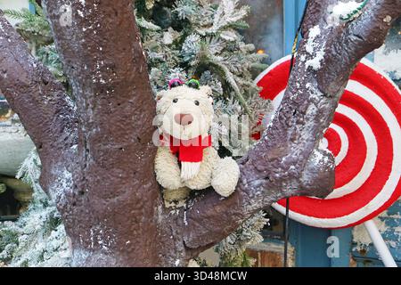 Adorable ours polaire jouet doux ourson sur un arbre de Noël recouvert de neige Banque D'Images