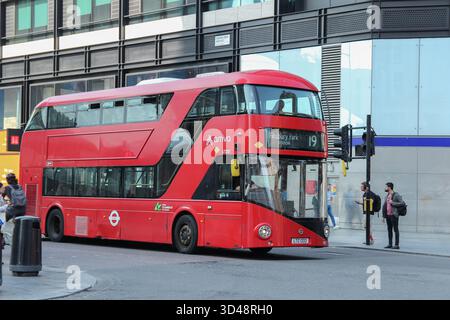 Un bus à impériale rouge s'arrête à un feu de circulation dans une rue animée de Londres, fournissant les transports publics pour les habitants et les touristes Banque D'Images