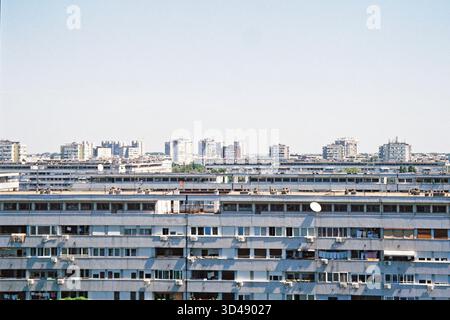 Vue téléobjectif grand angle des nouveaux bâtiments de Belgrade, géométrie brutale et lignes ensoleillées, blocs de tour éloignés dans des tons de film analogiques. Banque D'Images