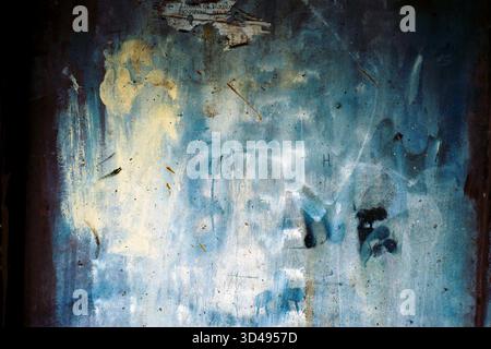 Mur en béton enduit de peinture dans un passage, texture de film analogique soulignant la surface rugueuse et la pourriture urbaine colorée. Banque D'Images