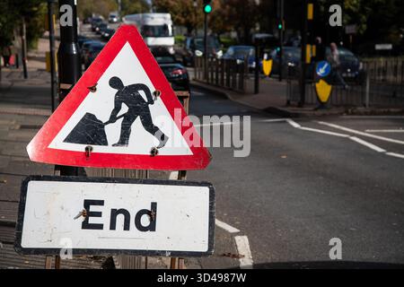 Triangle panneau d'avertissement des travaux routiers avec “end” sur un panneau blanc, placé au bord de la route au Royaume-Uni, indiquant la fin des travaux routiers. Banque D'Images
