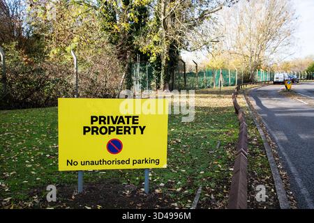 Panneau jaune « Private Property – No Unlimited parking » près d’une route verdoyante en Angleterre, symbolisant la restriction et l’accès privé à la terre. Banque D'Images