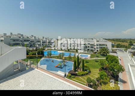Complexe familial avec piscine séparée pour enfants et profondeur progressivement décroissante, situé dans un jardin communautaire avec arbres ombragés et pavage antidérapant Banque D'Images