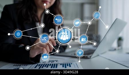 Une femme d'affaires interagit avec un ordinateur portable, présentant un concept dynamique de réseau de médias sociaux avec des icônes représentant divers canaux de communication et Banque D'Images