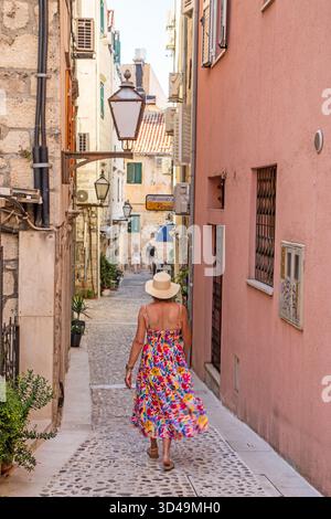 Femme touriste vacancier visitant la promenade à travers la jolie vieille rue pavée arrière dans la ville croate de Makarska Croatie Banque D'Images