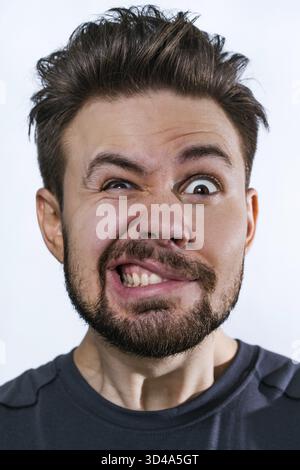 Jeune fou danger homme portrait émotionnel sur fond blanc Banque D'Images