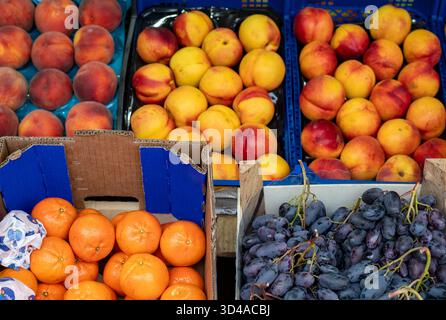 Des fruits frais comme des oranges, des nectarines, des raisins et des pêches exposés sur un marché fermier. Concept de marché des petits fermiers en plein air. Banque D'Images