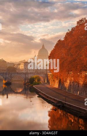 Automne et feuillage à Rome. Belles feuilles d'orange sycomore le long de la rivière Tibre dans la brume au coucher du soleil avec l'emblématique dôme St Peter Banque D'Images