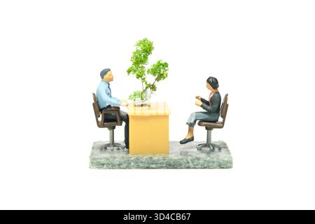 Miniature Tiny People jouet figure photographie. Concept de conversation professionnelle. Un homme d'affaires et une femme d'affaires assis sur une chaise à la salle de bureau. Isolat Banque D'Images