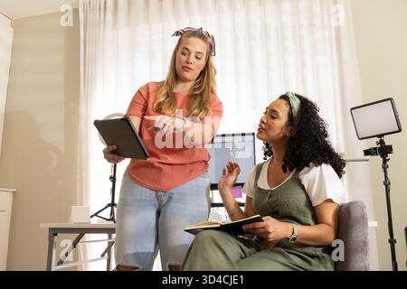 Collaboration de diverses collègues féminines discutant d'idées au bureau à domicile, avec tablette et ordinateur portable Banque D'Images
