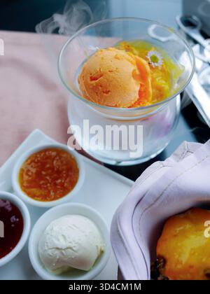Sorbet orange vibrant servi dans un bol en verre frais avec un effet de fumée subtil, style de nourriture moderne et lumineux idéal pour les menus de café, promotions de desserts, Banque D'Images