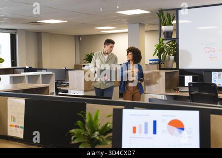 Marcher divers collègues collaborant dans un bureau ouvert, avec ordinateur portable et smartphone Banque D'Images