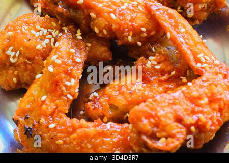 Gros plan d'ailes de poulet croustillantes et collantes généreusement enrobées d'un glaçage au miel et au sésame vif, salé et sucré. Idéal pour les menus ou les blogs alimentaires. Banque D'Images