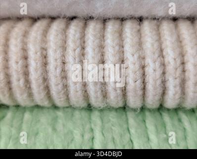 gros plan pile de tissus confortables roulés : blanc, tricot côtelé beige et tricot vert pâle Banque D'Images