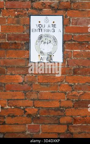 Sur un mur de briques rouges douces du Suffolk, un panneau d'avertissement de quartier est tellement fané et lavé que l'on craint qu'il ne soit plus un moyen de dissuasion si jamais il l'a été Banque D'Images