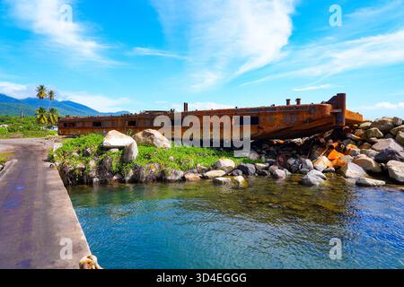 Barge rouillée sur un brise-lames de la ville de Nouvelle-Guinée sur la côte ouest de l'île de nouveaux Kitts dans la mer des Caraïbes Banque D'Images