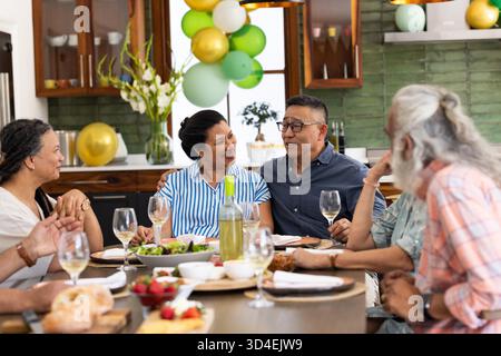 À la maison, des amis seniors ayant du vin et discutant pendant la réunion de fête. Socialisation, amitié, célébration, hospitalité, loisirs, senior Lifestyle || autorisation du modèle Banque D'Images