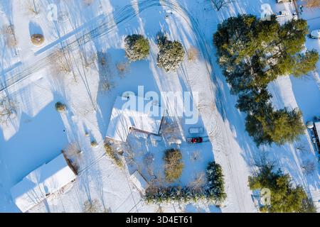 Vue aérienne du paysage enneigé avec des maisons, des arbres, chemin sinueux dans un village américain rural calme Banque D'Images