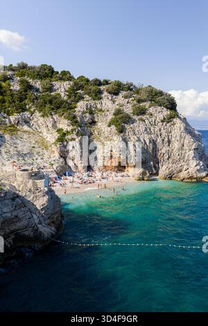 Vue aérienne des eaux turquoises rencontre la côte accidentée, embrassant une plage animée nichée sous les falaises imposantes, Brsec, Istrie, Croatie. Banque D'Images