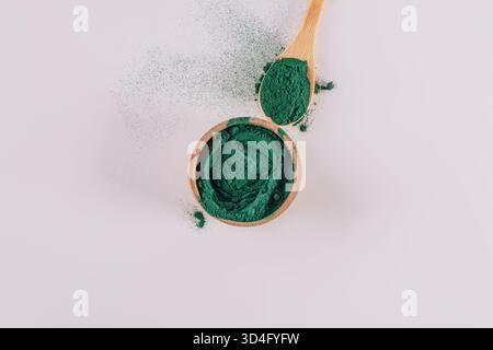 bol en bois et cuillère remplis de poudre de spiruline naturelle. superaliment bleu, vert. Détox. Supplément organique de perte de poids. vue de dessus. fond blanc Banque D'Images