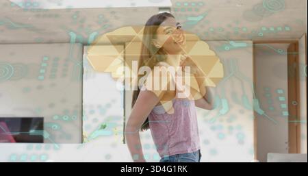 Femme souriante portant un haut rose, un Jean bleu debout dans le salon, avec des superpositions TV et AR Banque D'Images