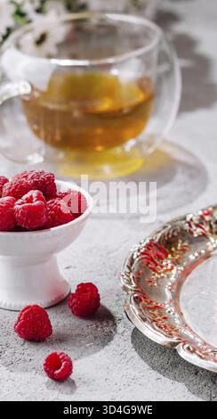 Nourriture, framboises dans un bol et une tasse de thé en verre Banque D'Images