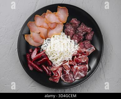 Nourriture, vue aérienne d'une sélection de charcuteries avec viandes et fromages sur une assiette noire Banque D'Images
