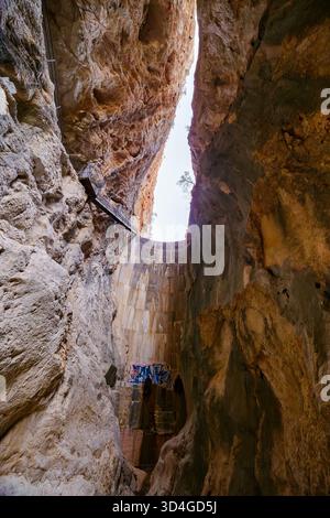 Une vue spectaculaire à angle bas regardant le mur de béton incurvé du barrage Isbert, flanqué d'imposantes falaises rocheuses abruptes qui se rétrécissent jusqu'à un morceau de Banque D'Images