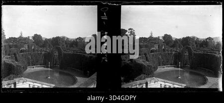 Capturée entre 1899 et 1910, cette image montre une fontaine et un labyrinthe avec des montagnes en arrière-plan, créant un paysage pittoresque et serein. Banque D'Images