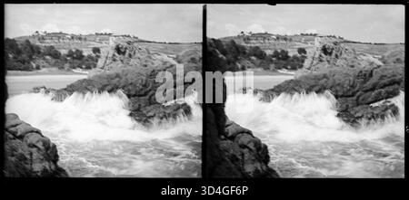 Les vagues se brisent contre les rochers le long de la côte de Santa Cristina d'Aro. L'image, prise par Josep Domènech i Sàbat entre 1922 et 1934, représente la dynamique marine côtière et les caractéristiques rocheuses du littoral. Banque D'Images