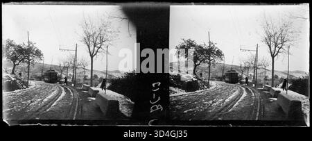 Image historique entre 1899 et 1910 montrant un tramway passant dans une rue enneigée avec deux personnes présentes, capturée par Josep Maria Armengol i Bas. Banque D'Images
