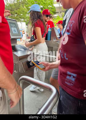 Un homme en chemise rouge tient un téléphone portable et regarde une machine. Système de vérification des billets à Citizen Bank Park, stade des Philadelphia Phill Banque D'Images