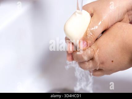 Les mains d'un enfant sont lavées avec du savon sous un robinet, soulignant l'importance de l'hygiène. Cette image met en évidence la pratique de l'ha propre Banque D'Images
