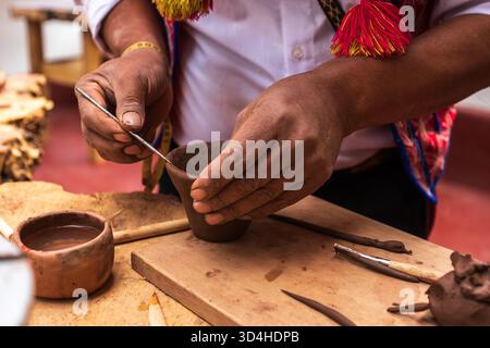 Gros plan de l'artisan quechua façonnant une coupe d'argile lors d'un cours de poterie à l'atelier de céramique. Pisac, région de Cusco, Pérou, 2025-05-29. Banque D'Images