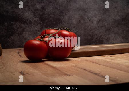 Tomates fraîches mûries de vigne prêtes à faire des conserves sur une planche à découper en bois Banque D'Images