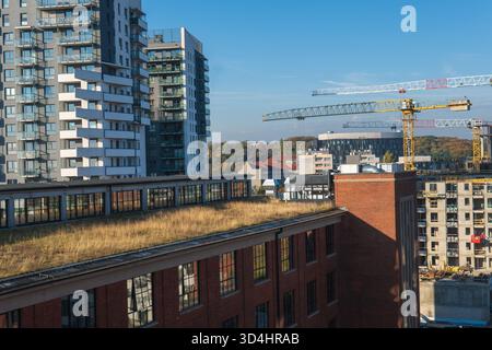 Vue de jour depuis un appartement moderne à Gdansk, Pologne montre un bâtiment industriel en briques avec un toit vert, de nouvelles tours avec des balcons décalés, et y Banque D'Images