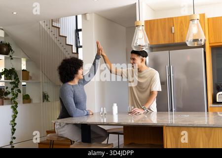 Des amis masculins diversifiés à travers l'île de marbre dans la cuisine de la maison, avec bouteille de pilule et verres Banque D'Images