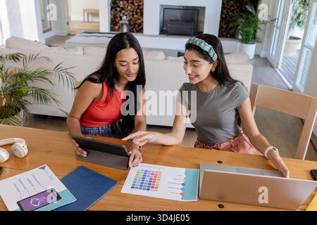 Collaborer diverses amies féminines concevant à la table en bois dans le salon avec des échantillons de couleur Banque D'Images