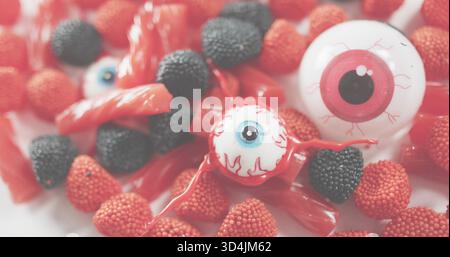 Affichage des bonbons d'Halloween sur la surface blanche, globes oculaires roses et bleus, réglisse rouge, gommes perlées Banque D'Images