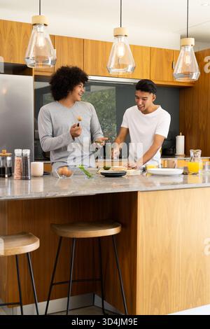 Hacher avocat divers amis masculins préparant le petit déjeuner dans une cuisine moderne, avec îlot de marbre Banque D'Images