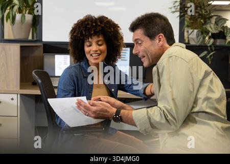 Examen de divers collègues examen de documents imprimés au bureau à l'aide de deux moniteurs Banque D'Images