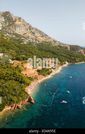 Vue aérienne des eaux turquoise rencontre la côte accidentée, couronnée par des forêts verdoyantes et des montagnes imposantes, Sveti Stefan, municipalité de Budva, Monten Banque D'Images